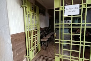 A room with a green gate, a sign reading 'PARSIK HILL PALACE,' and several round tables. - Parsik Hill Palace III (Thane)