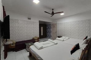 A hotel room with two beds, a desk, a chair, a television, and a ceiling fan. - Parsik Hill Palace III (Thane)