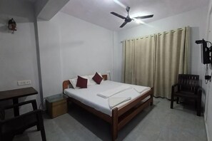 A bedroom with a single bed, a desk, a chair, a ceiling fan, and a window with curtains. - Parsik Hill Palace III (Thane)