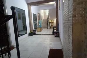 A hallway with a staircase leading to an upper floor, a water dispenser, and a trash bin. - Parsik Hill Palace III (Thane)