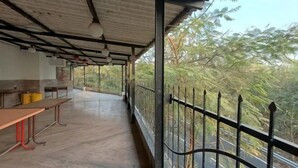 Un espace extérieur abrité, doté de bancs et d’une rambarde, qui offre une vue sur une route et des arbres.