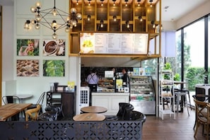A café with a menu board, seating area, and a counter with a person behind it.