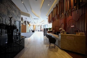 A hotel lobby with a reception desk, seating area, and a modern interior design.
