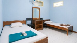 A room with two wooden beds, a desk, a chair, a mirror, and a ceiling fan. - Hotel Budi Famili Budget Syariah (Ciamis)