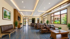 A hotel lobby with a reception desk, seating area, and large windows. - Hotel Budi Famili Budget Syariah (Ciamis)