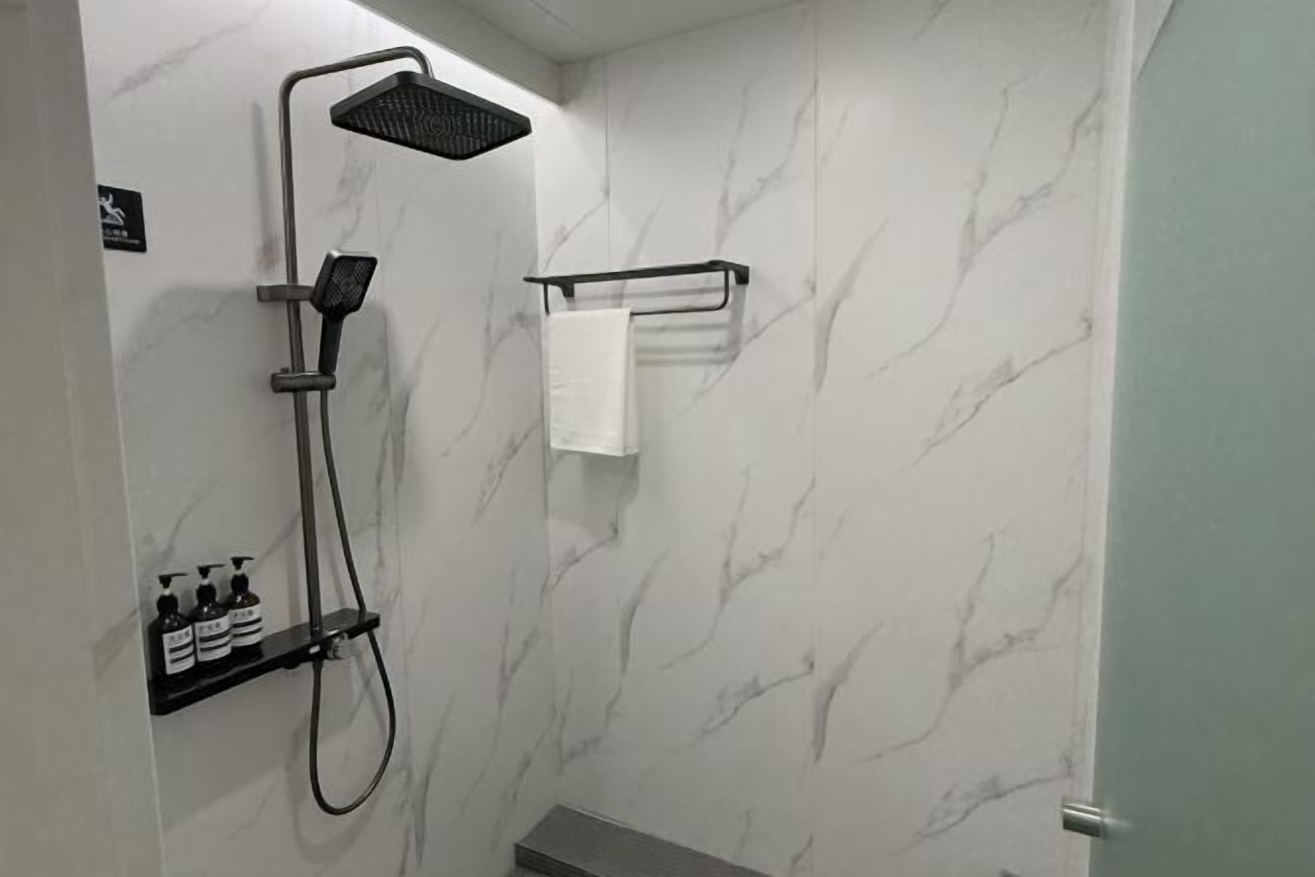 A bathroom with a shower, a towel rack, and a shelf with toiletries.