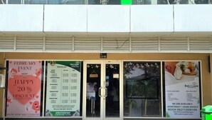 A hotel entrance with a Valentine's Day event poster, a price list, and a Bali Luxe advertisement. - Trivium Terrace Apartment Lippo Cikarang (Min Stay 3 Nights) (South Cikarang)