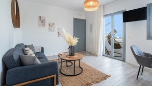 Una sala de estar moderna con un sofá, una mesa de centro redonda y un televisor montado en la pared.