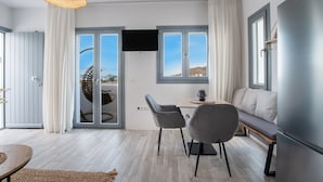 Una sala de estar moderna con sofá, dos sillones, una mesa, un televisor de pantalla plana y un ventanal con vistas.