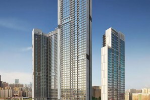 Zwei Hochhäuser mit modernem architektonischen Design, viele Fenster und ein klarer Himmel im Hintergrund.
