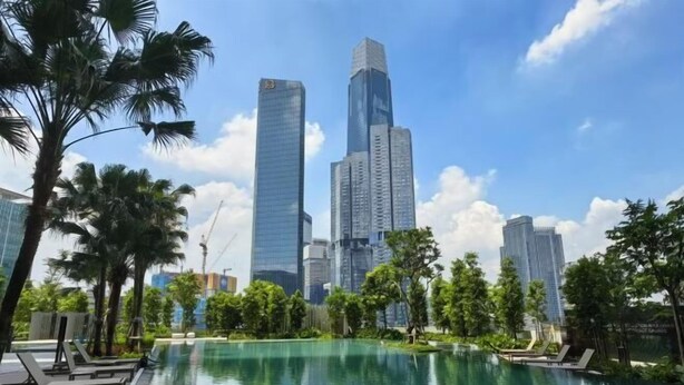 A swimming pool with lounge chairs, surrounded by palm trees and modern buildings in the background. - TRX AGILE Bukit Bintang Superior 8 Pax Family Suites (Kuala Lumpur)