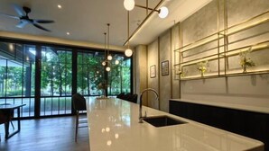 A modern kitchen with a large island, pendant lighting, and a view of greenery outside. - TRX AGILE Bukit Bintang Superior 8 Pax Family Suites (Kuala Lumpur)