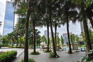 A rooftop pool area with lounge chairs and palm trees, surrounded by buildings. - TRX AGILE Bukit Bintang Superior 8 Pax Family Suites (Kuala Lumpur)
