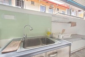 Eine Küche mit einem Edelstahlspülbecken, einem Schneidebrett und einem weißen Ablageschrank.