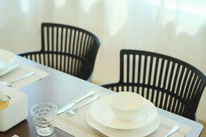 A dining table set with white plates, a bowl, cutlery, and a glass. - Hidden Gems in China Town, 2 Bedrooms (Bangkok)