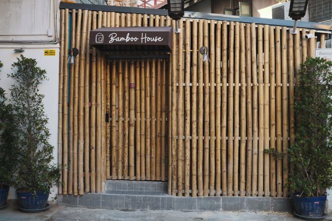 A bamboo fence entrance to Bamboo House with a sign above the door.