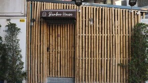 Ingresso di una casa con recinto in bambù, con un cartello sopra la porta.