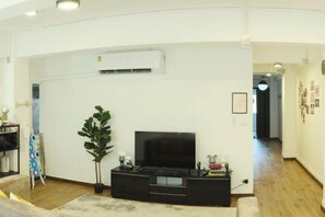 A living room with a flat-screen TV, a potted plant, and a black entertainment unit. - Hidden Gems in China Town, 2 Bedrooms (Bangkok)