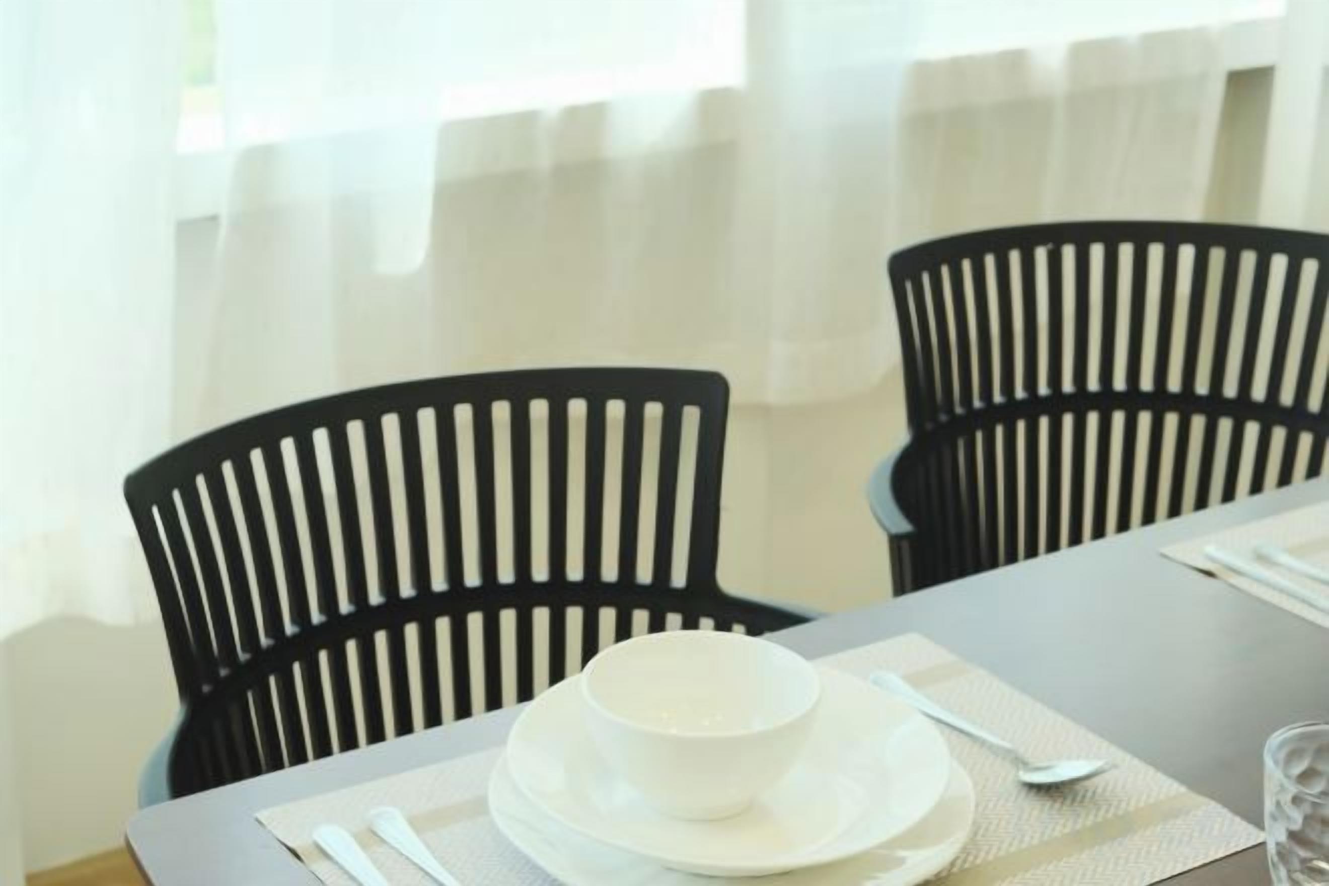 A dining table set with a white bowl, a spoon, and a glass.