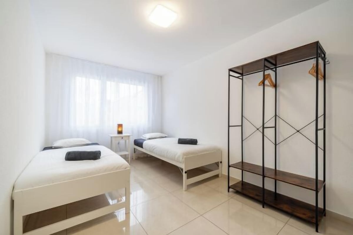 A room with two beds, a wardrobe, and a small table.