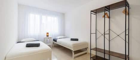 A room with two beds, a wardrobe, and a small table.