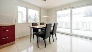 Un comedor con una mesa y sillas, ventanas amplias y vistas a un paisaje nevado.