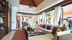 A spacious living area with a sofa, coffee table, and a view of the outdoors. - Baan Chang (Koh Samui)