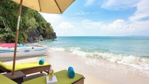A beachside lounge with a wooden bench, a yellow umbrella, and a view of the ocean. - Baan Chang (Koh Samui)