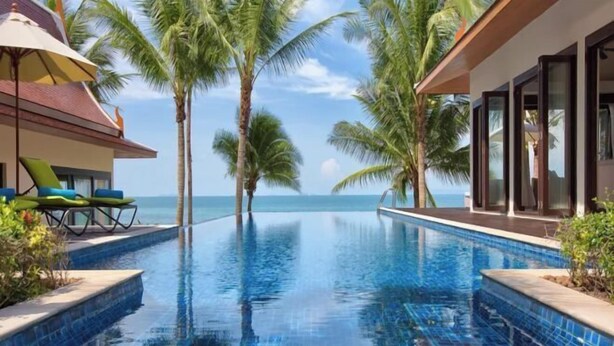 A swimming pool with a view of the ocean, surrounded by palm trees and a building with large windows. - Baan Chang (Koh Samui)