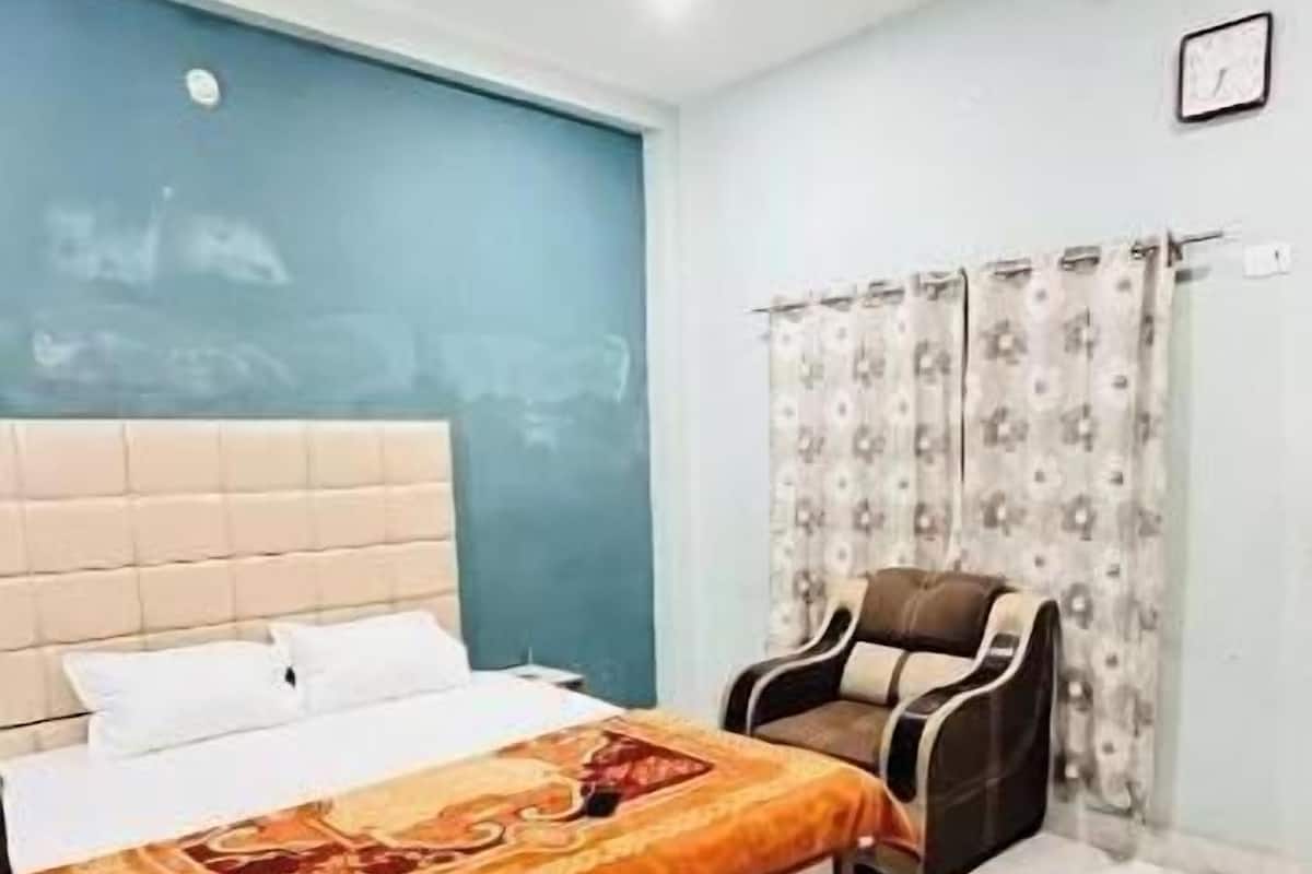 A bedroom with a bed, a ceiling fan, a chair, and a window with curtains.
