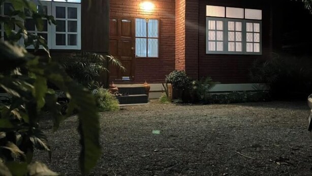 En bygning med murstensfacade, store vinduer og en velholdt have.