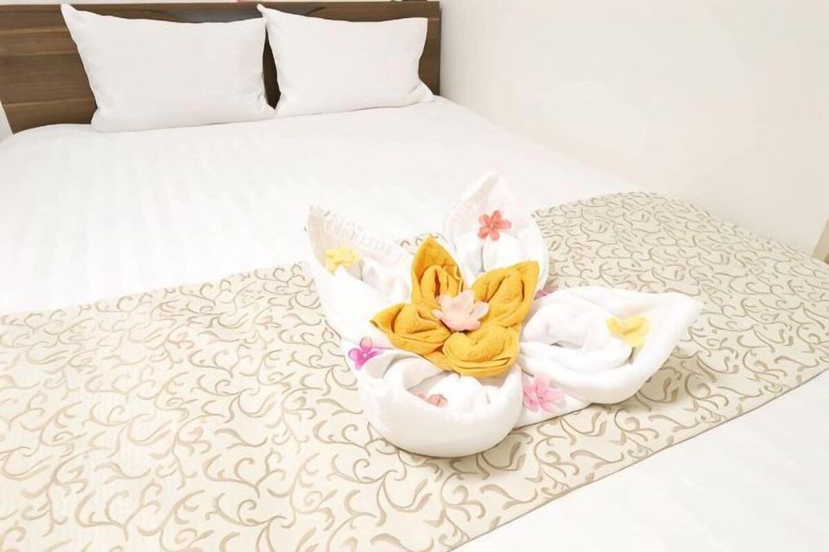 A neatly made bed with a patterned bedspread and a decorative towel arrangement.