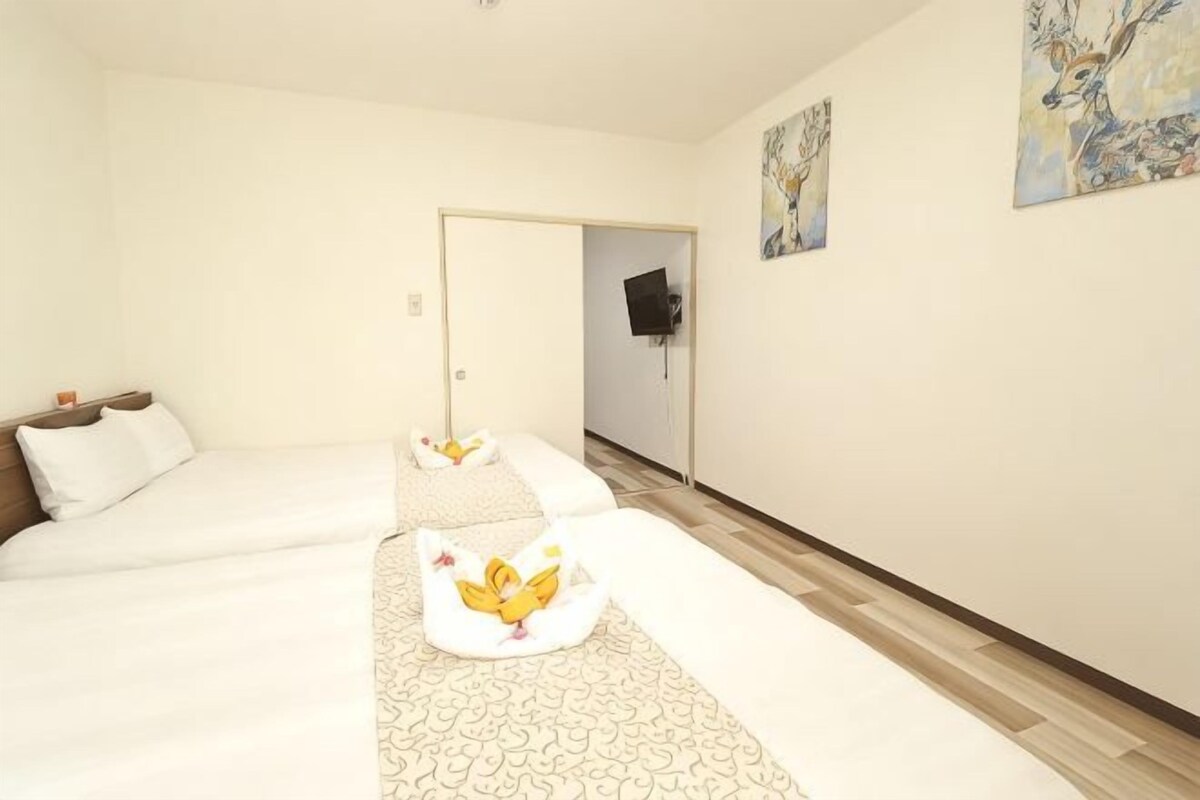 A hotel room with two beds, a TV, and artwork on the walls.