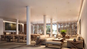 Eine geräumige Lobby mit hohen Decken, großen Säulen und verschiedenen Sitzbereichen, darunter Sofas und Tische.