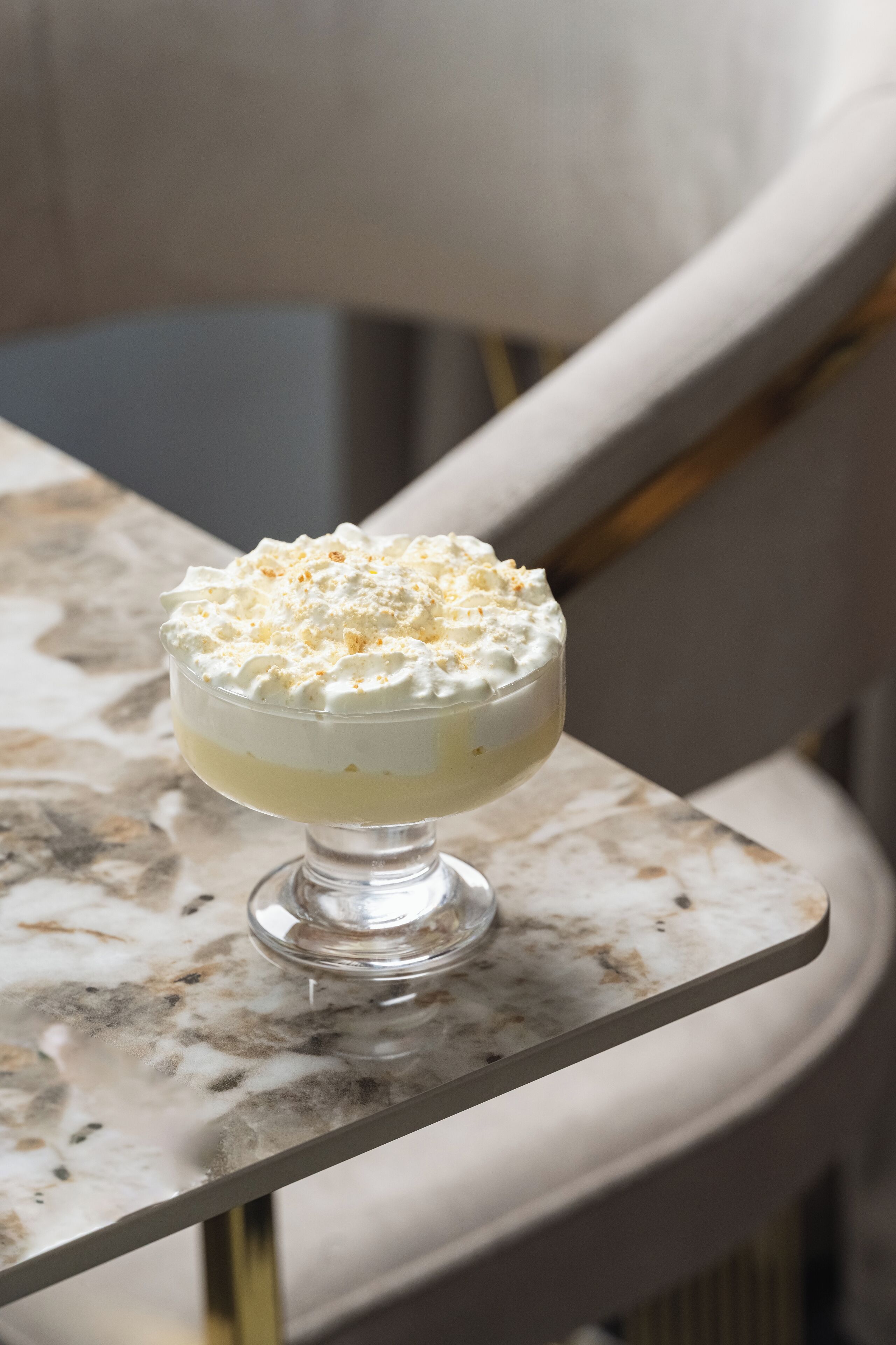 A dessert in a glass bowl on a marble table.