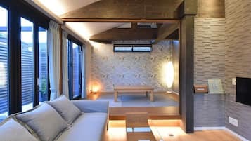 A modern living room with a sofa, a wooden coffee table, and a bench. There is a fireplace and a TV mounted on the wall.