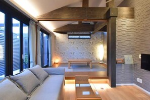 A modern living room with a sofa, a wooden coffee table, and a bench. There is a fireplace and a TV mounted on the wall.