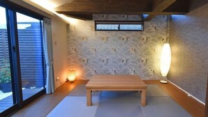 A room with a wooden bench, tatami mats, a stone wall with a bird pattern, a window with blinds, and a ceiling with exposed beams. - KandoStay Asakusa East Terrace (Tokyo)