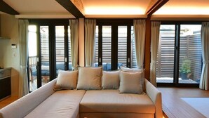 A modern living room with a sofa, a coffee table, and large windows with blinds. - KandoStay Asakusa East Terrace (Tokyo)