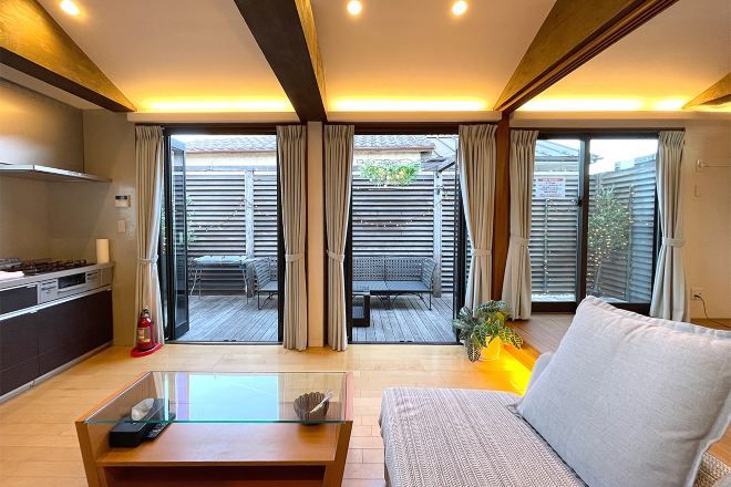 A modern living room with a sofa, a glass coffee table, and a view of an outdoor patio area with a table and chairs.
