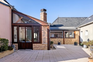 A courtyard with a brick building, a glass door entrance, and potted plants.