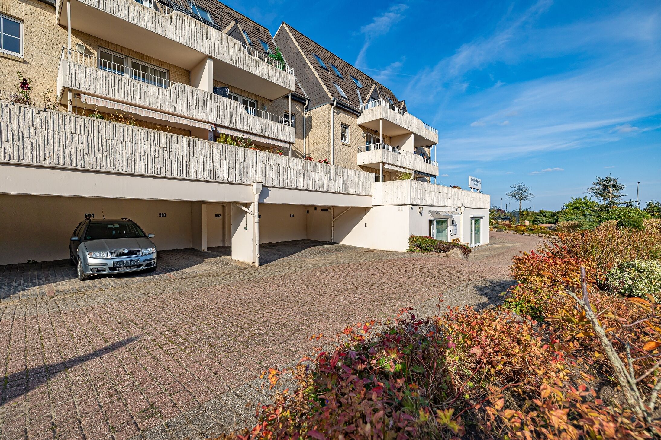 A multi-story residential building with a car parked in the driveway.