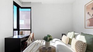 A bedroom with a bed, a desk, a window, and a wall-mounted artwork. - A Chic 2BR Apt Near Melbourne Uni, FREE Parking (Carlton)