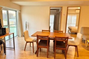 Un comedor con una mesa y sillas de madera, un televisor y un sofá al fondo.