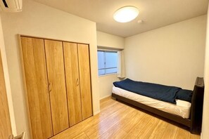 A bedroom with a single bed, wooden wardrobe, and a window. - Luxurious stay with a rooftop balcony of over 100 square meters! (Tokyo)