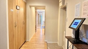 Un pasillo con armarios de madera, un quiosco informativo digital y suelo alfombrado.