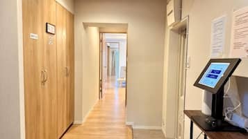 A hallway with wooden wardrobes, a digital information kiosk, and a carpeted floor.