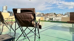 Terraza en la azotea con una silla y un paraguas, con vistas a un paisaje urbano.