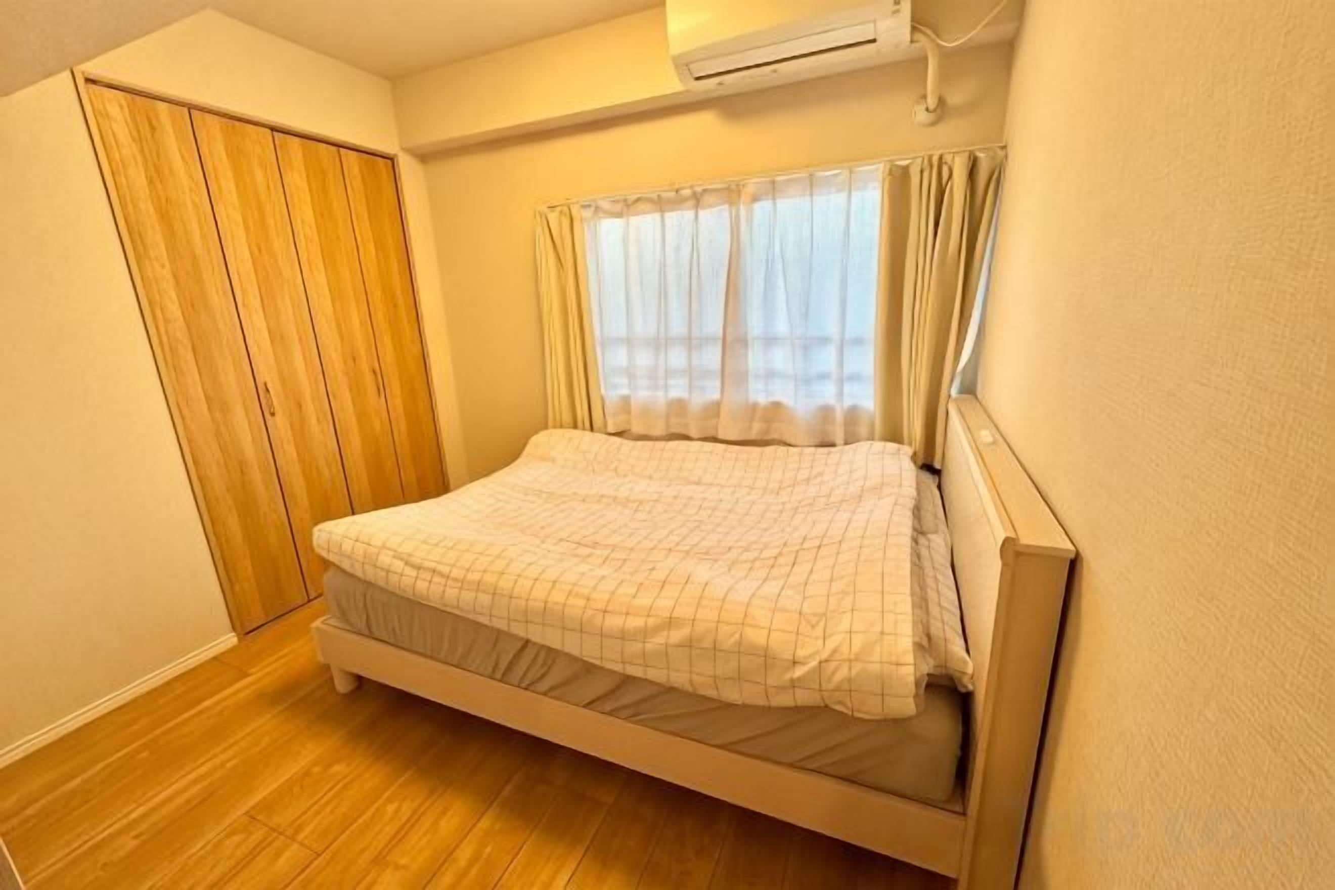 Ein Schlafzimmer mit einem Bett, einem Holzschrank und einem Fenster mit Vorhängen.