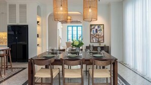 A dining area with a long table set for six, surrounded by wooden chairs with cushioned seats. Two woven pendant lights hang above the table. - domdomHOUSE Villa - 1min to beach (Ha Long)